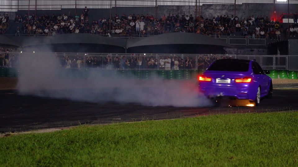 Carro esportivo em movimento com rastros de luz vermelha à noite